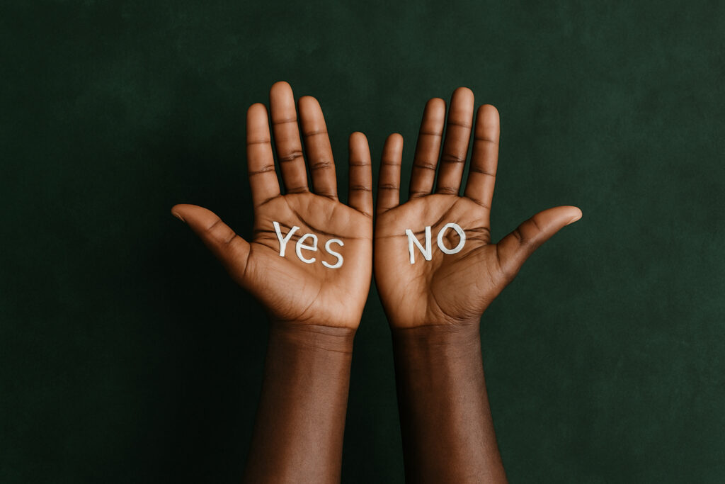 Two hands raised with “Yes” and “No” written on the palms, symbolizing choice and decision-making